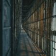 Langer, verlassener Gefängniskorridor mit rostigen Metallgittern und Fenstern